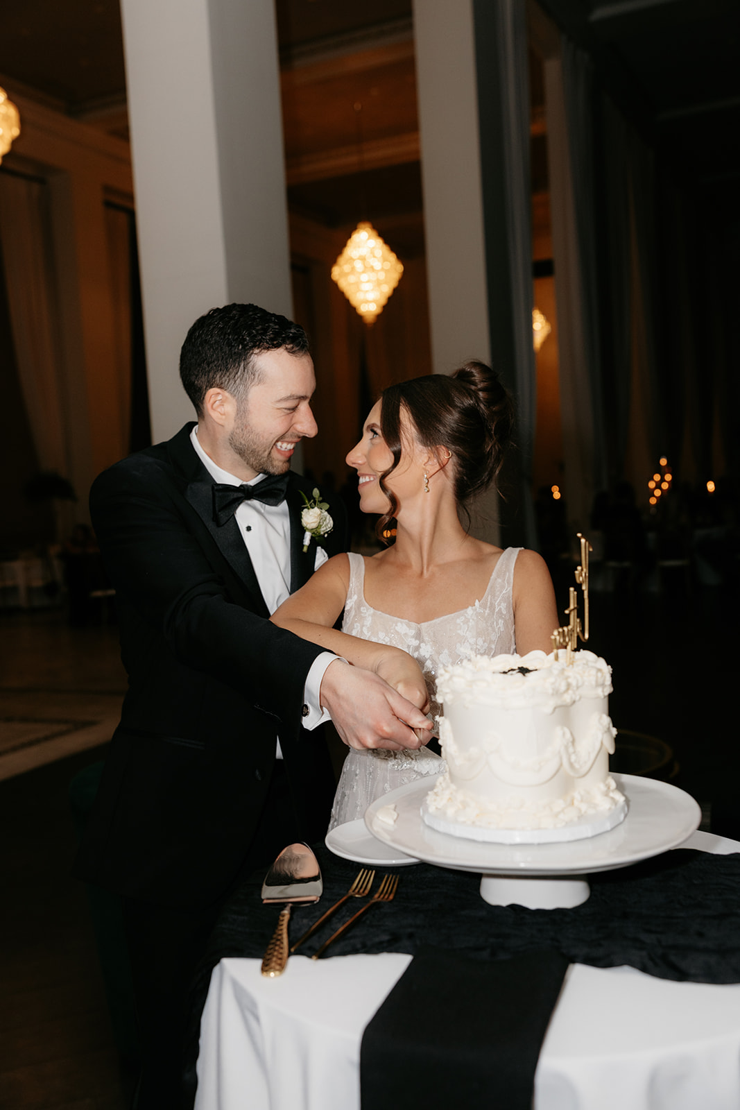 bride and groom cutting cake smiling at each other