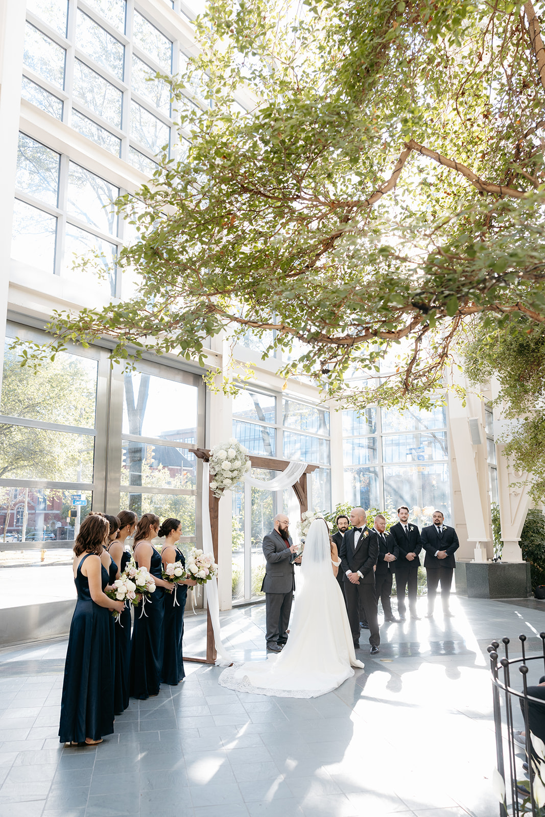 ceremony at the wintergarden with sun peaking through the tall glass windows
